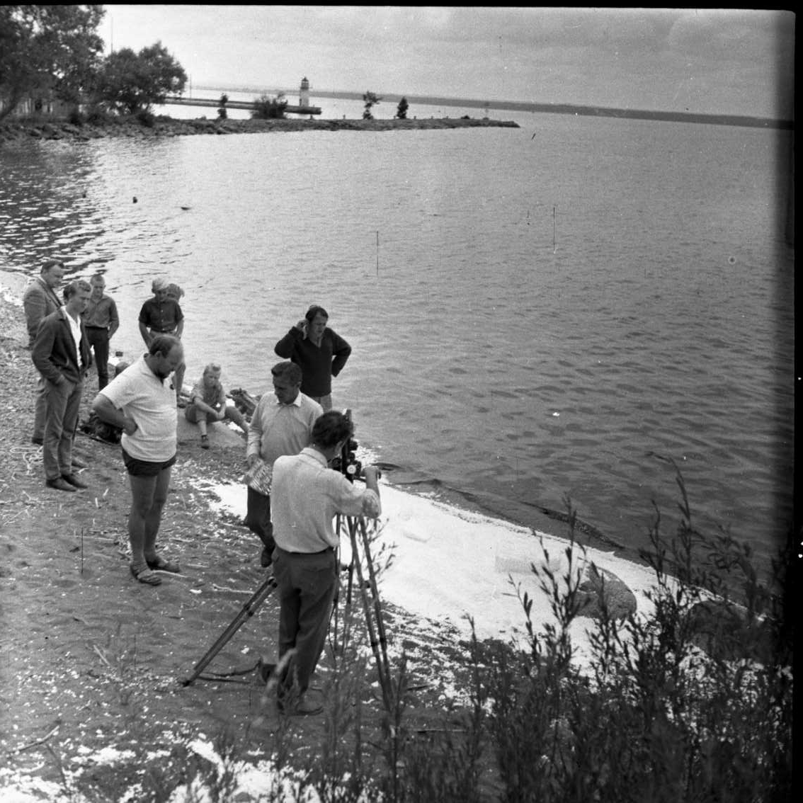 Ett filmteam vid Vätterstranden, norr om hamne i Gränna, lite publik i bakgrunden. Konstgjord snö på stranden.