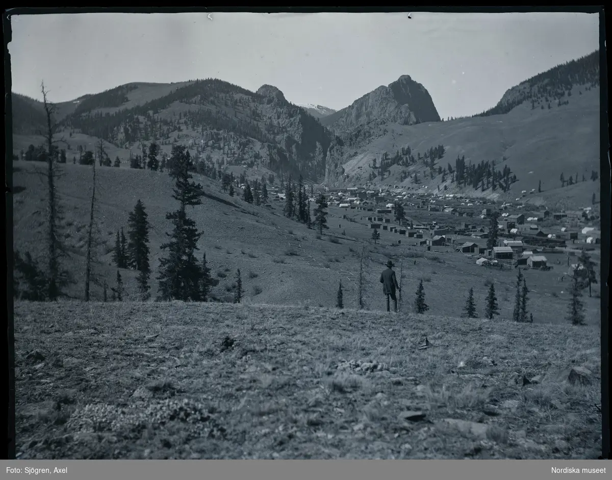 En man står och blickar ut över ett bergigt landskap och bebyggelse. Colorado, USA.