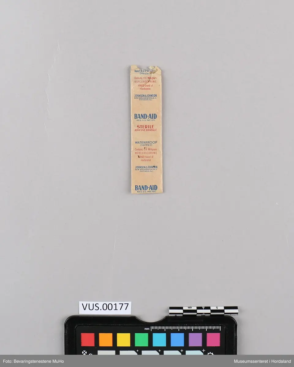 Rektangulært, hvitt plaster inni en rektangulær, beige papirlomme med bruksanvisning.