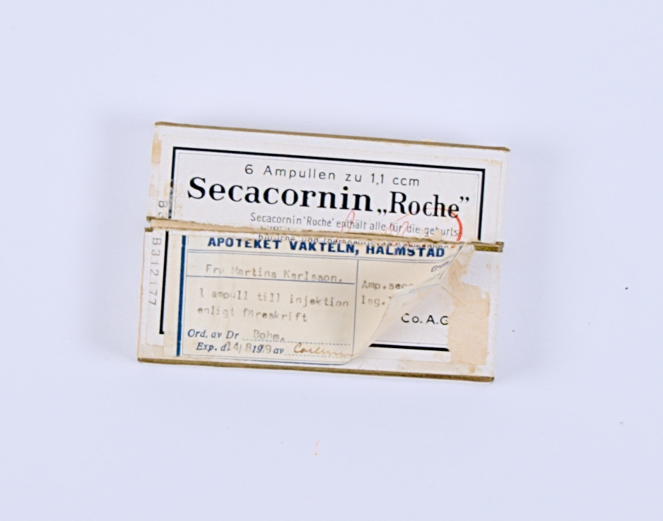 Medicinförpackning av papp. På förpackningen ett fastklistrat recept. Förpackning innehåller fem stycken ampuller av läkemedlet Secacornin.