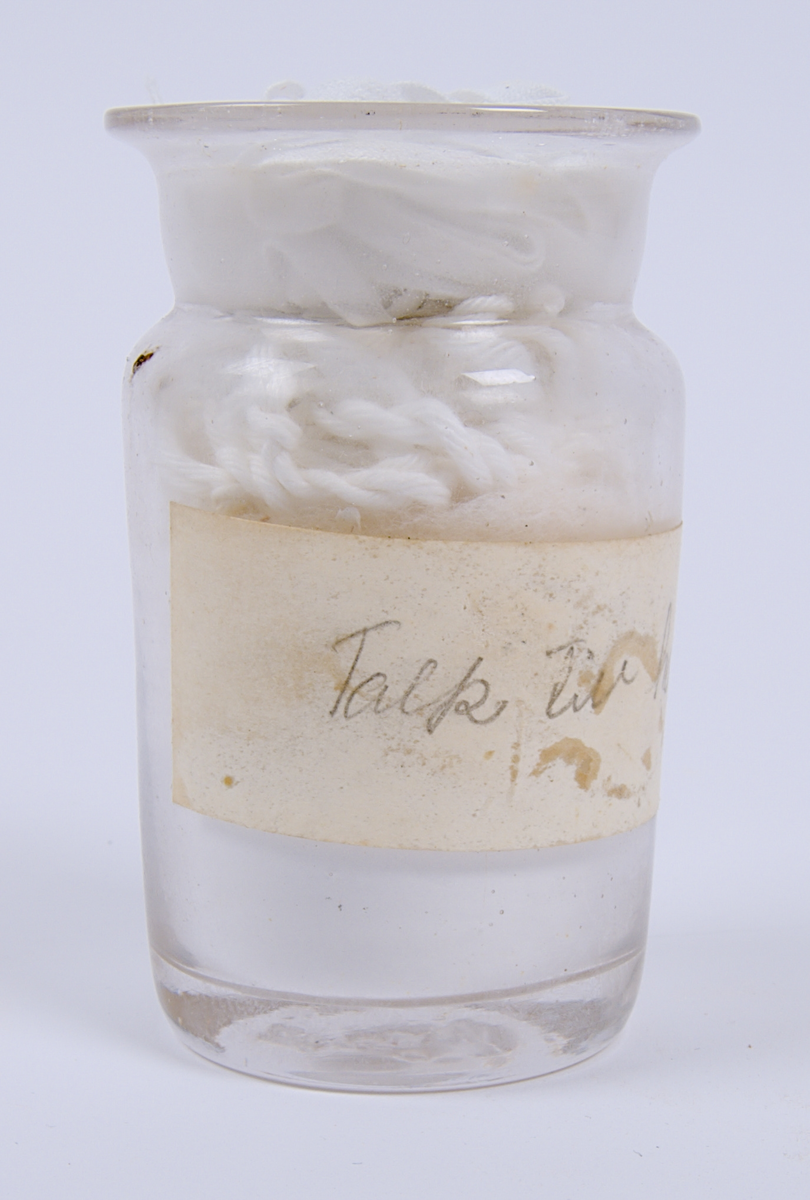 Glasburk innehållande "Talk för handskar", enligt den handskrivna etiketten som sitter på burken.