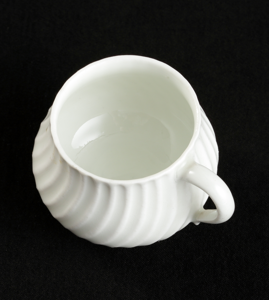 Krämkopp med lock, av porslin. Vitglaserad.
Något bukig modell, vridna räfflor å lock och knopp. På locket en skulpterad blomma som knopp.

Inskrivet i huvudbok 1967.