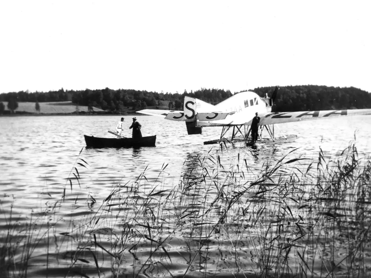 Hydroplan på Uttran utanför Bergsbacke, Sjövretsvägen.

Fotot togs den 14 juli 1925 då Einar Lagrelius, med hatt i roddbåten, kom för att gratulera Louis "Issa" Ramström på hennes 60-årsdag. Einar L hyrde hydroplanet. På pontonen står piloten. Den andre mannen i båten är Stig Walin, systerson till Louis R. Stig W blev tidigt föräldralös då hans föräldrar gick ner sig på isen mellan Bergsbacke och Vretaberg. Louis och Carl Ramström (Kalle Ram) adopterade Stig W och hans syster.

Uppgiftslämnare: Ingrid Walin 1989.