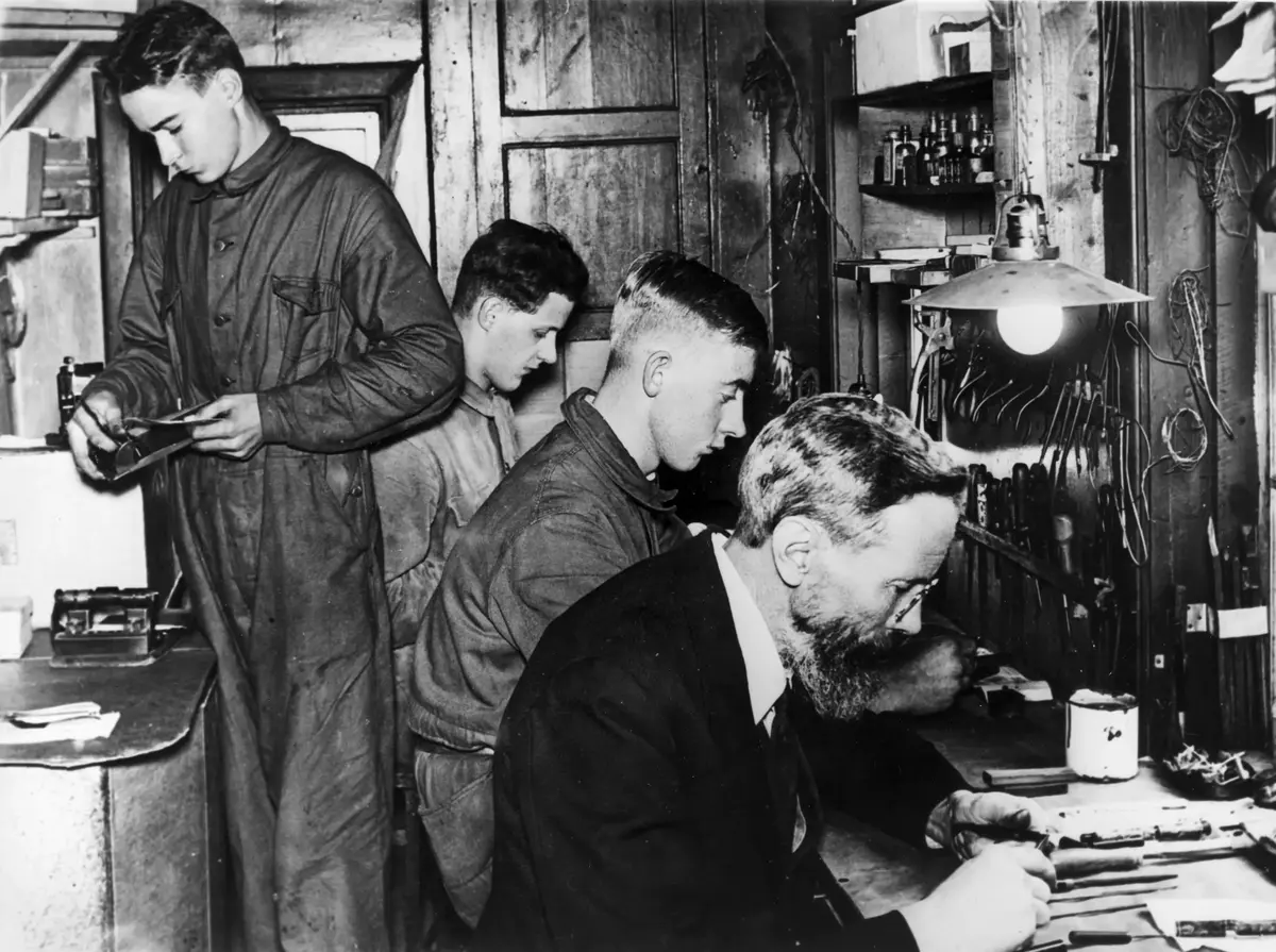 Interiör av verkstad med fyra personer som arbetar.

Engbergs mekaniska verkstad, Axelbergsvägen 21 (rivet) i början av 1930-talet. Företaget var specialiserat på tillverkning av åskådningsmaterial för fysiklaborationer åt Norstedts & söner. Man kontrollerade också alla reservoirpennor åt Swanströms samt reparerade dessa. Företagets ägare och ledare Karl Engberg sitter längst fram.

Från vänster: Stig Andersson, Karl-Erik Larsson, Lennart Johansson och Karl Engberg.

Uppgiftslämnare: Åke Engberg 1993.