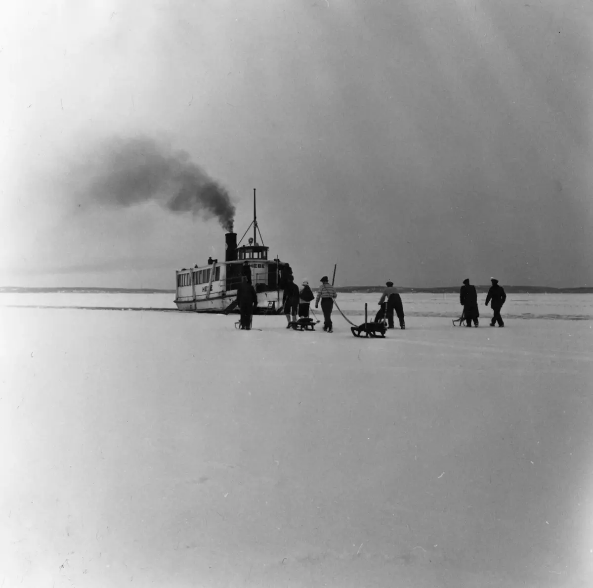 Isvinter. 1940-tal. Gunnar Öhman och Holger Olsson fick hämta varorna till affären ända ute vid farleden mot Dalarö när båten Hebe inte kunde ta sig fram längre i isen.