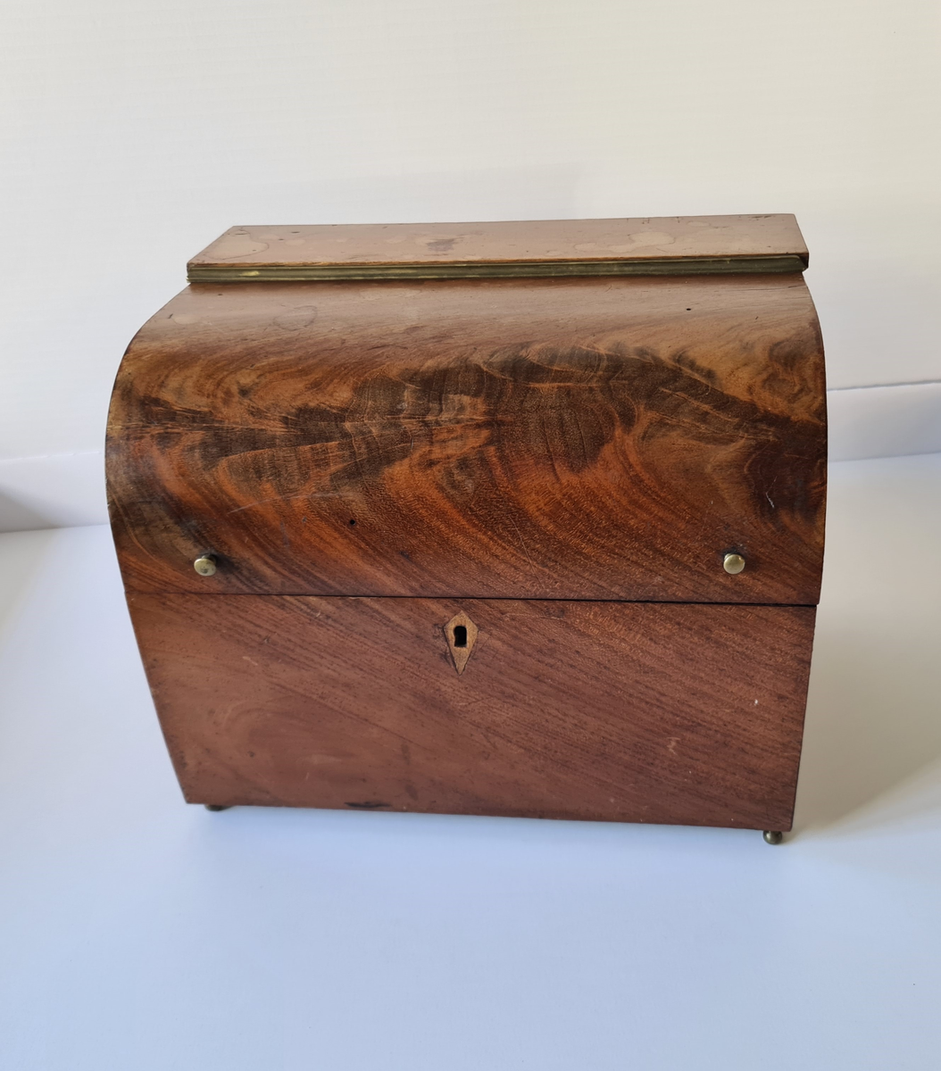 Reiseskrin med seks karafler og to glass. Skrinet er utformet i lys mahogny. Plass innvendig til seks karafler med propp, og to små stettglass. Skrinet er inndelt i seks seksjoner og trukket med mørk blå fløyel nede i rommene og (blass) rød fløyel oppe ved kantene og under lokket. I lokket er det også et spor til å feste to glass. Disse er det ikke plass til når skrinet lukkes. Hengslet lokk. Nøkkelhull foran. Nøkkel mangler.