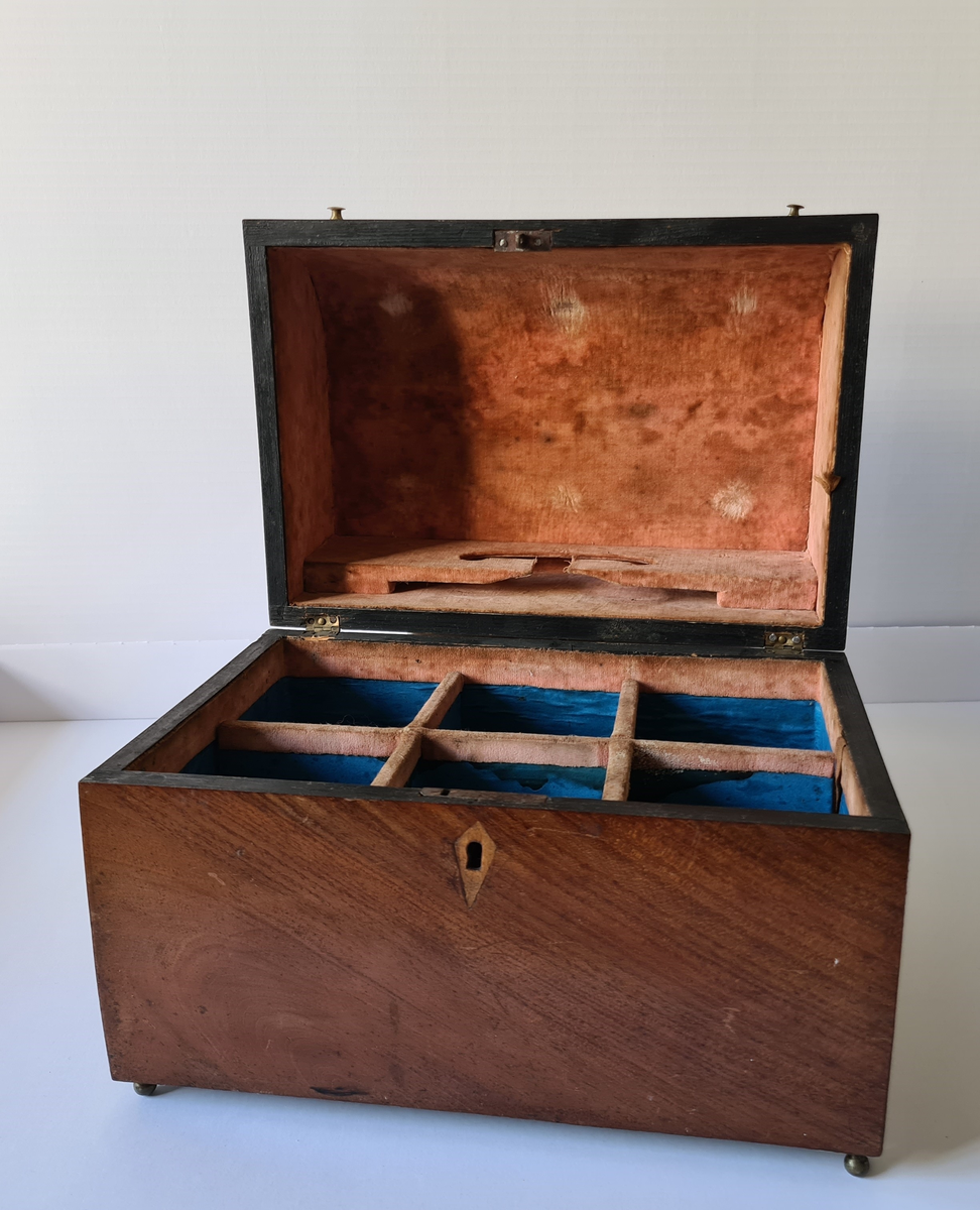 Reiseskrin med seks karafler og to glass. Skrinet er utformet i lys mahogny. Plass innvendig til seks karafler med propp, og to små stettglass. Skrinet er inndelt i seks seksjoner og trukket med mørk blå fløyel nede i rommene og (blass) rød fløyel oppe ved kantene og under lokket. I lokket er det også et spor til å feste to glass. Disse er det ikke plass til når skrinet lukkes. Hengslet lokk. Nøkkelhull foran. Nøkkel mangler.