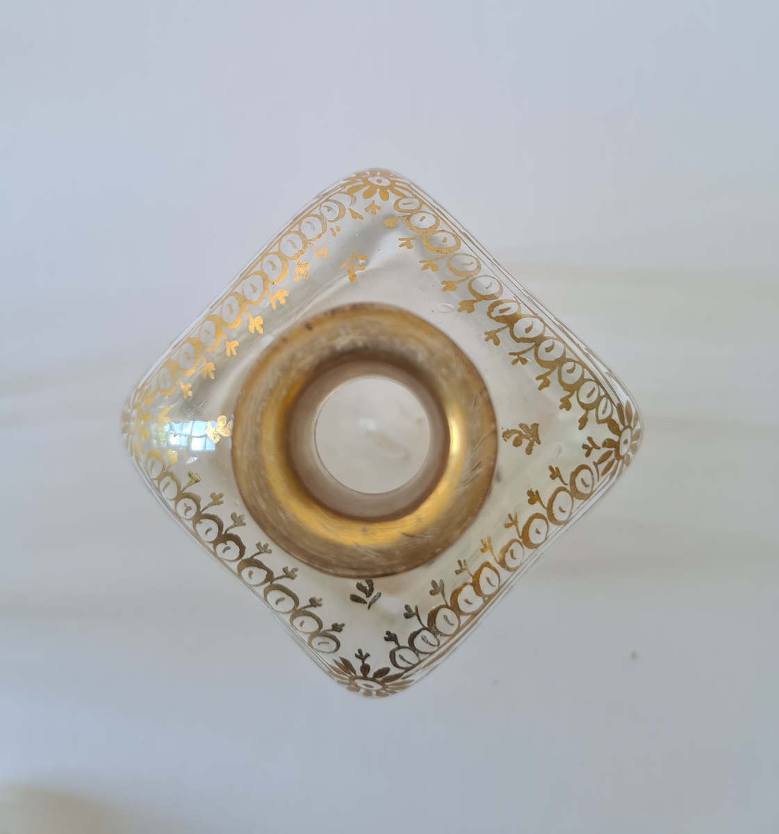 Karaffel av glass med tilhørende propp. Forgyllet dekor rundt halsen. Firkantet form, noe avrundet ved halsen.