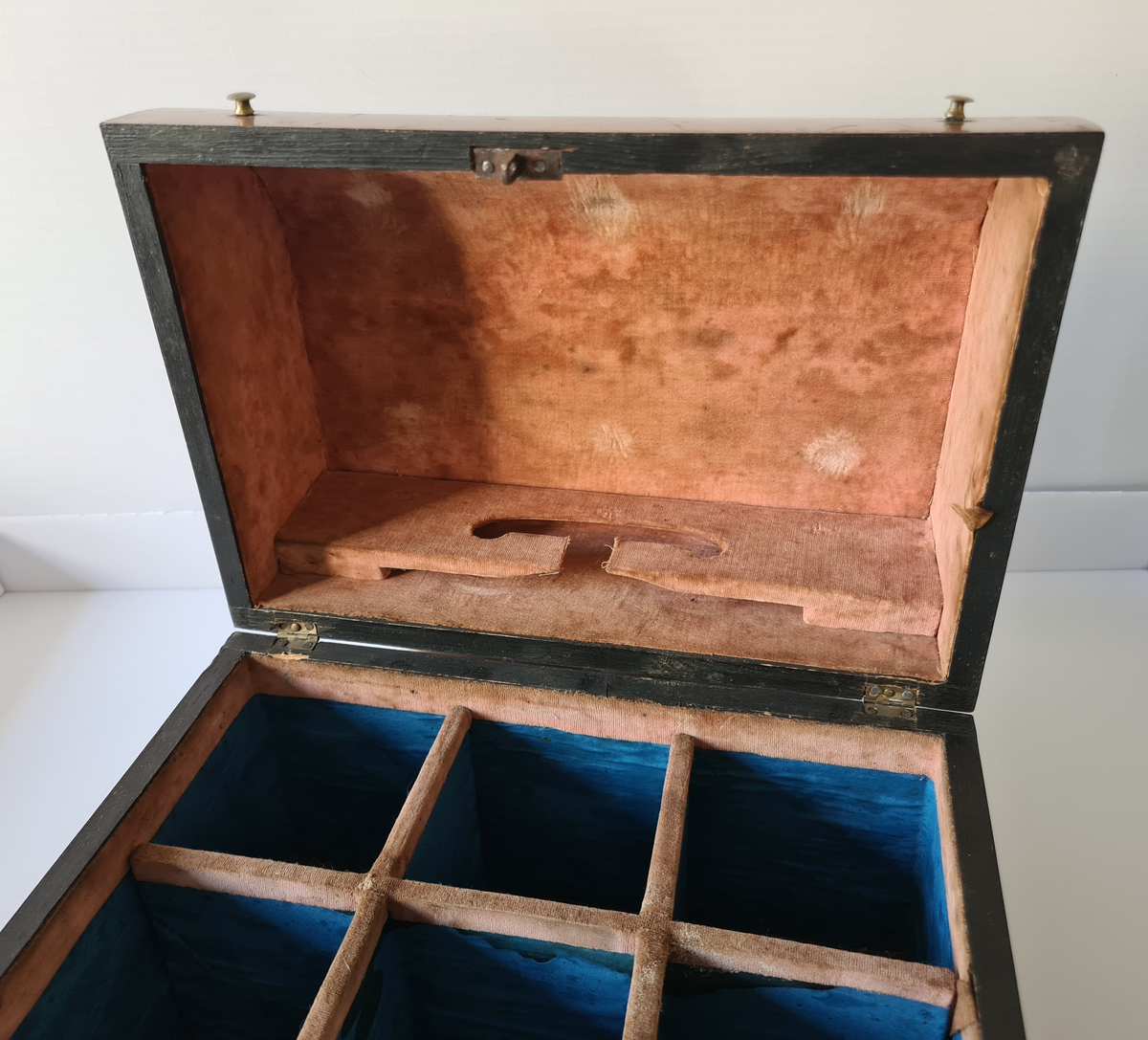 Reiseskrin med seks karafler og to glass. Skrinet er utformet i lys mahogny. Plass innvendig til seks karafler med propp, og to små stettglass. Skrinet er inndelt i seks seksjoner og trukket med mørk blå fløyel nede i rommene og (blass) rød fløyel oppe ved kantene og under lokket. I lokket er det også et spor til å feste to glass. Disse er det ikke plass til når skrinet lukkes. Hengslet lokk. Nøkkelhull foran. Nøkkel mangler.