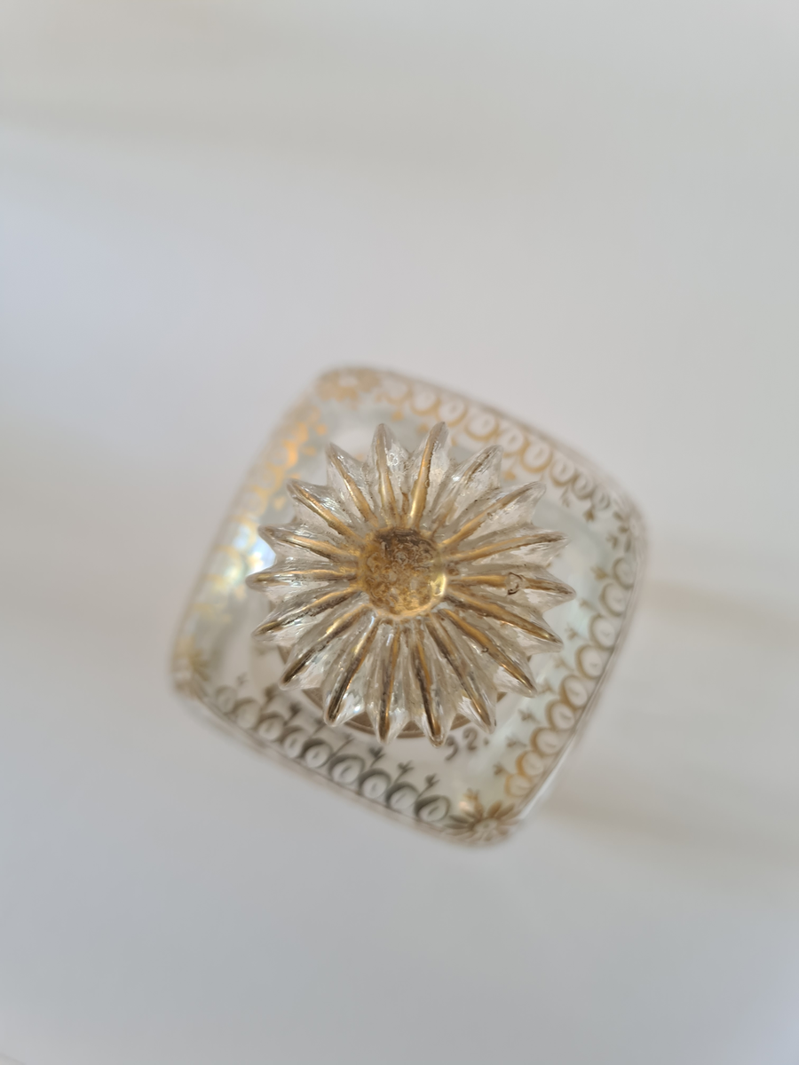 Karaffel av glass med tilhørende propp. Forgyllet dekor rundt halsen. Firkantet form, noe avrundet ved halsen.