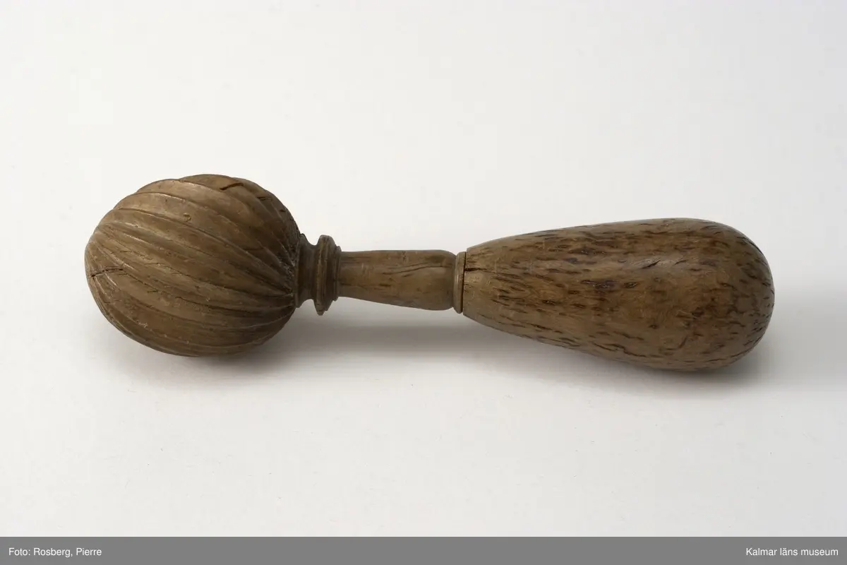 KLM 8330. Smörklubba, av trä. Skaftet i ändan päronformigt. Främre delen äggformig med  breda, skarpryggade åsar.