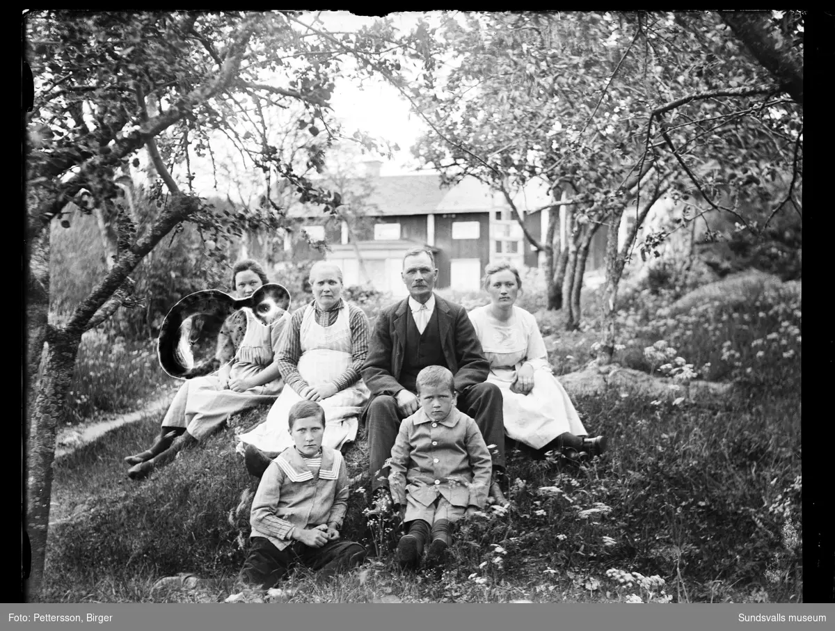Familjeporträtt i trädgården med mangårdsbyggnaden i bakgrunden. En kvinna, en man, två flickor och två pojkar.