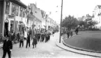 Kortege med fanbärare och musikkår framför unga och gamla på Brahegatan i Gränna.