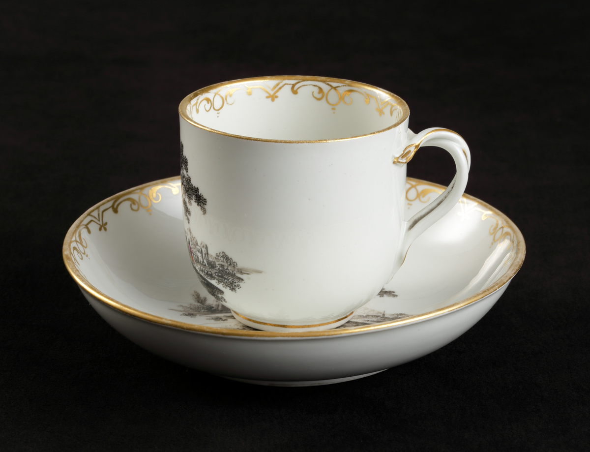 Kopp med fat av porslin. Koppen i bägarform. Fatet skålformigt. 
Dekorerad med ruinlandskap i svart camaïeu, med färglagda figurer. 
Kring kanterna spetsliknande bårder i guld. 

Inskrivet i huvudbok 1967.