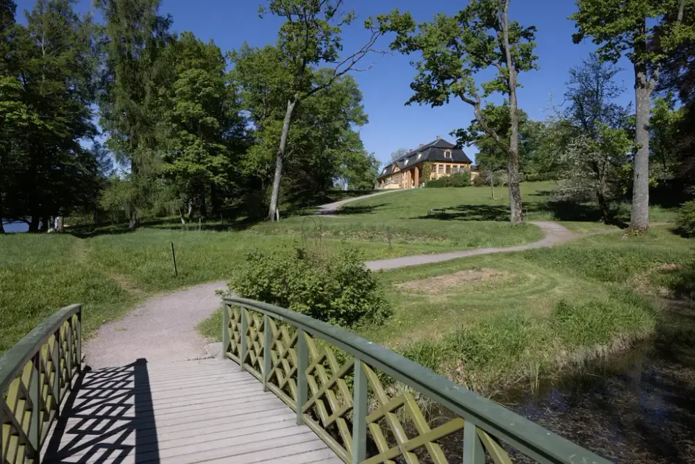 En bro og en sti leder gjennom parken opp til hovedbygningen på Bogstad gård. 