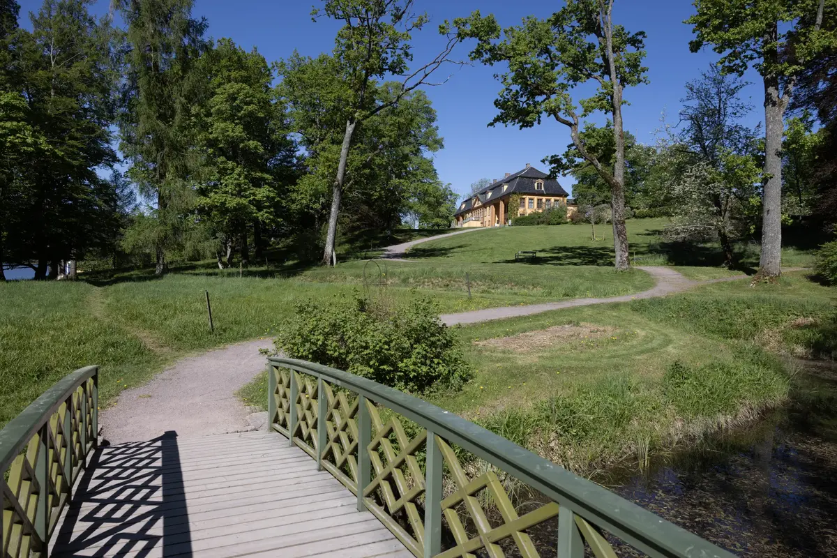 En bro og en sti leder gjennom parken opp til hovedbygningen på Bogstad gård. 
