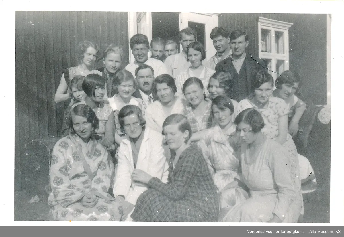 Et gruppebilde av 22 personer, kvinner, menn og ungdommer, på trappen til Talvik Tuberkulosehjem.