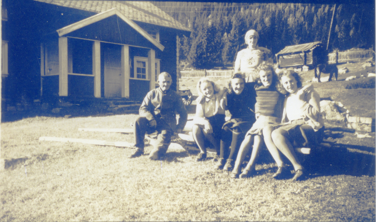 Gruppe på gårdstun. Bildet er fra N. Gudbrandsrud, Rukkedalen. Bak Mette Gudbrandsrud, f.Sletten. Fra venstre foran: Ola Gudbrandsrud, Hanna Fosserud, gift Lie, Gunhild Klype f. Gudbrandsrud, Gunhild Bråten Merudningen, Ukjent.
