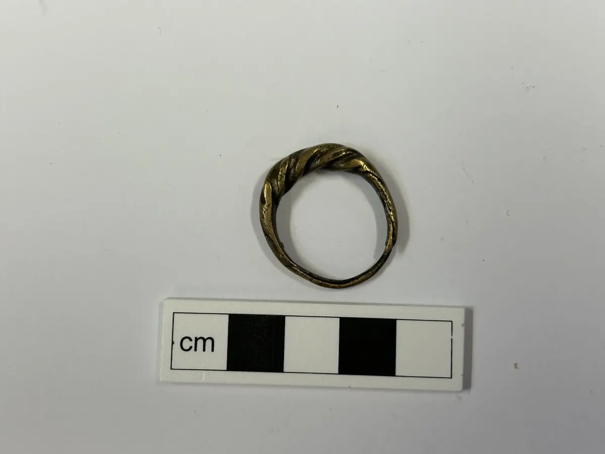 AV BRONS, ÖPPEN, TORSERAD, ÄNDARNA TILLSPETSADE, DIAM. 2,5 - 2,7 CM. FUNNEN VID BETGALLRING I EN ÅKER MELLAN JÄRNVÄGEN OCH ROMA MYR, INVID ROMA STATION, AV ARBETAREN K. NILSSON, UGGLAUSE ESKELHEM. KÖP NR: 341.