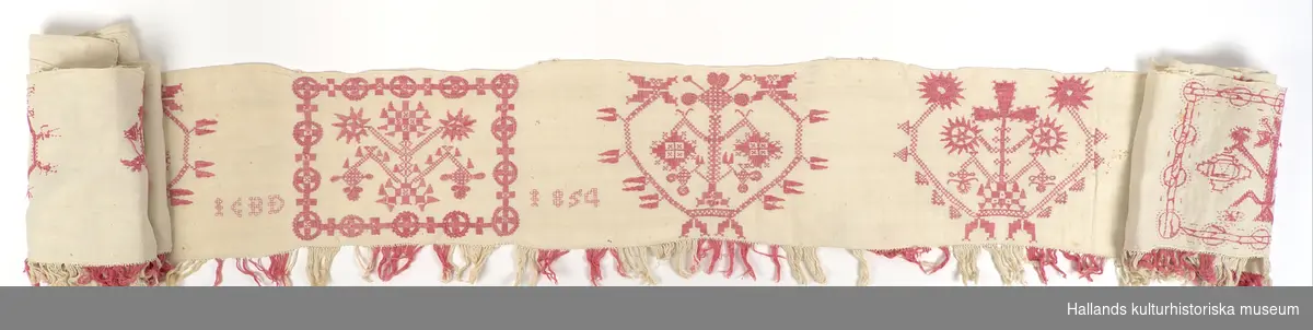 Hängkläde av vit linnelärft. Rikt broderad i hela sin längd med hallandsmönster av rödfärgat bomullsgarn. Sammanlagt 13 broderade mönsterpartier, varav samtliga mönster unika. I hängklädets mitt finns en broderad märkning: "ICBD 1854".

Nedtill längs hängklädets hela längd en list av påsydda fransar i omväxlande rött- och vitfärgat bomullsgarn.