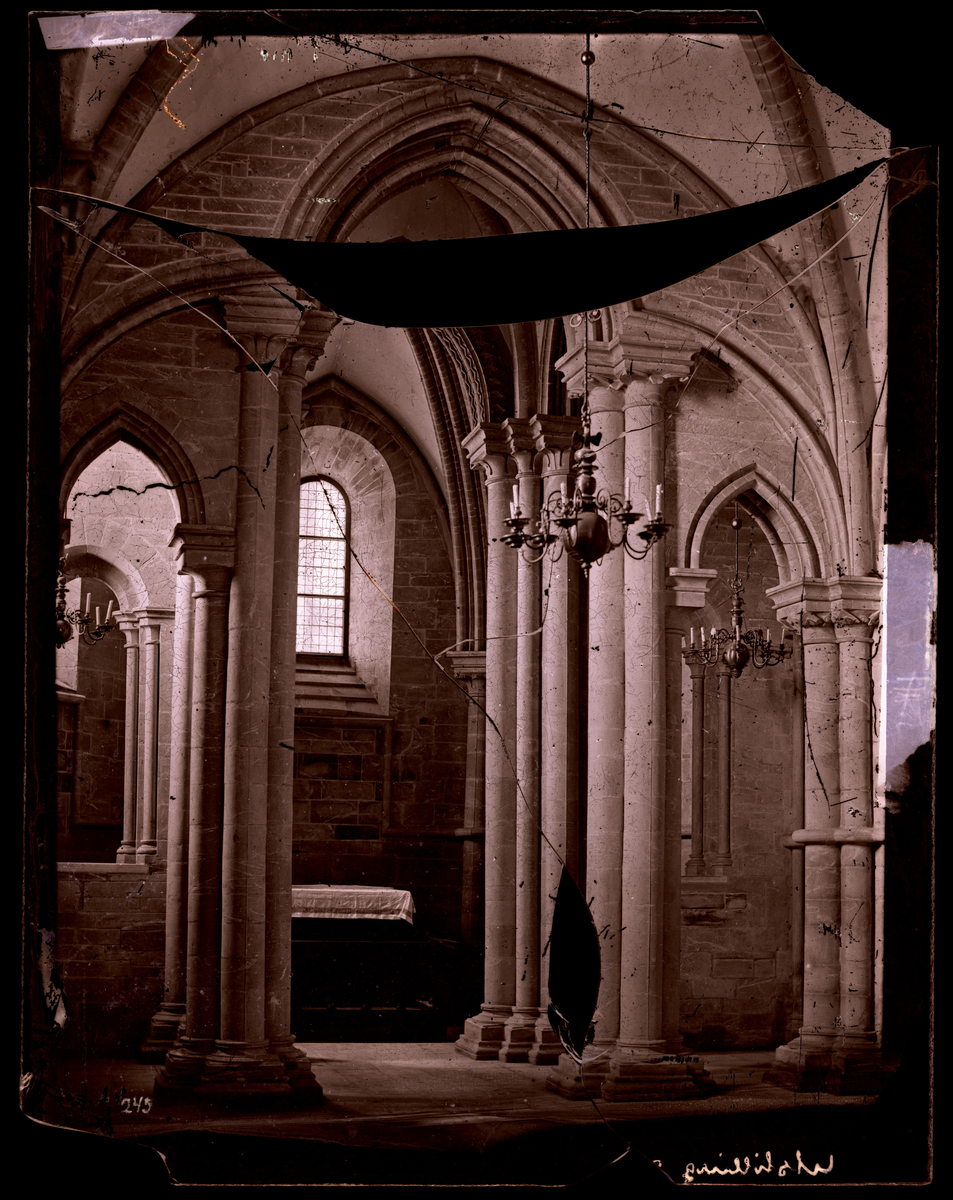 Korbue og alter i Kapittelhuset (også kalt Mariakapellet, Skrudhuset og sakristiet) i Nidarosdomen. Ifølge Hovedkatalog over fotografier er bildet tatt etter restaurering; et arbeid som pågikk i perioden 1869-1871.
Se også NDR.000257 for samme motiv. 