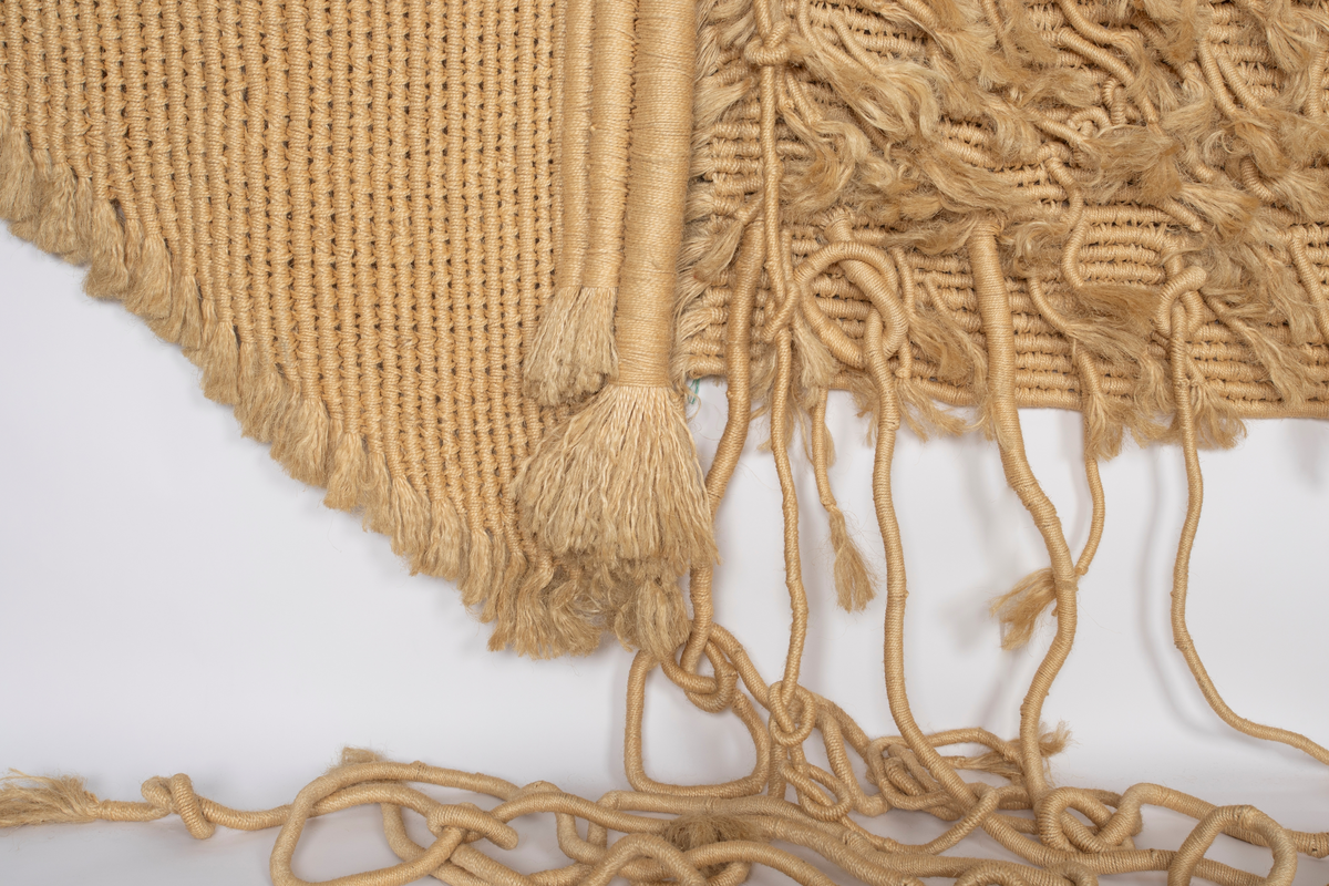 Billedvev av naturfarget sisal. Bunter av omviklede renningstråder er delvis sammenvevd til flater, delvis festet til flaten som lange pølser og løsthengende haler. Tekstilet er vevd i tre deler med et rektangulært midtfelt mellom to tilnærmet rektangulære sidefelt. Sidefeltene er glatte, mens midtfeltet fremstår frodig med lange og korte nedhengende duskehaler, de lengste så lange at de kryper ned fra veggen og utover gulvet.