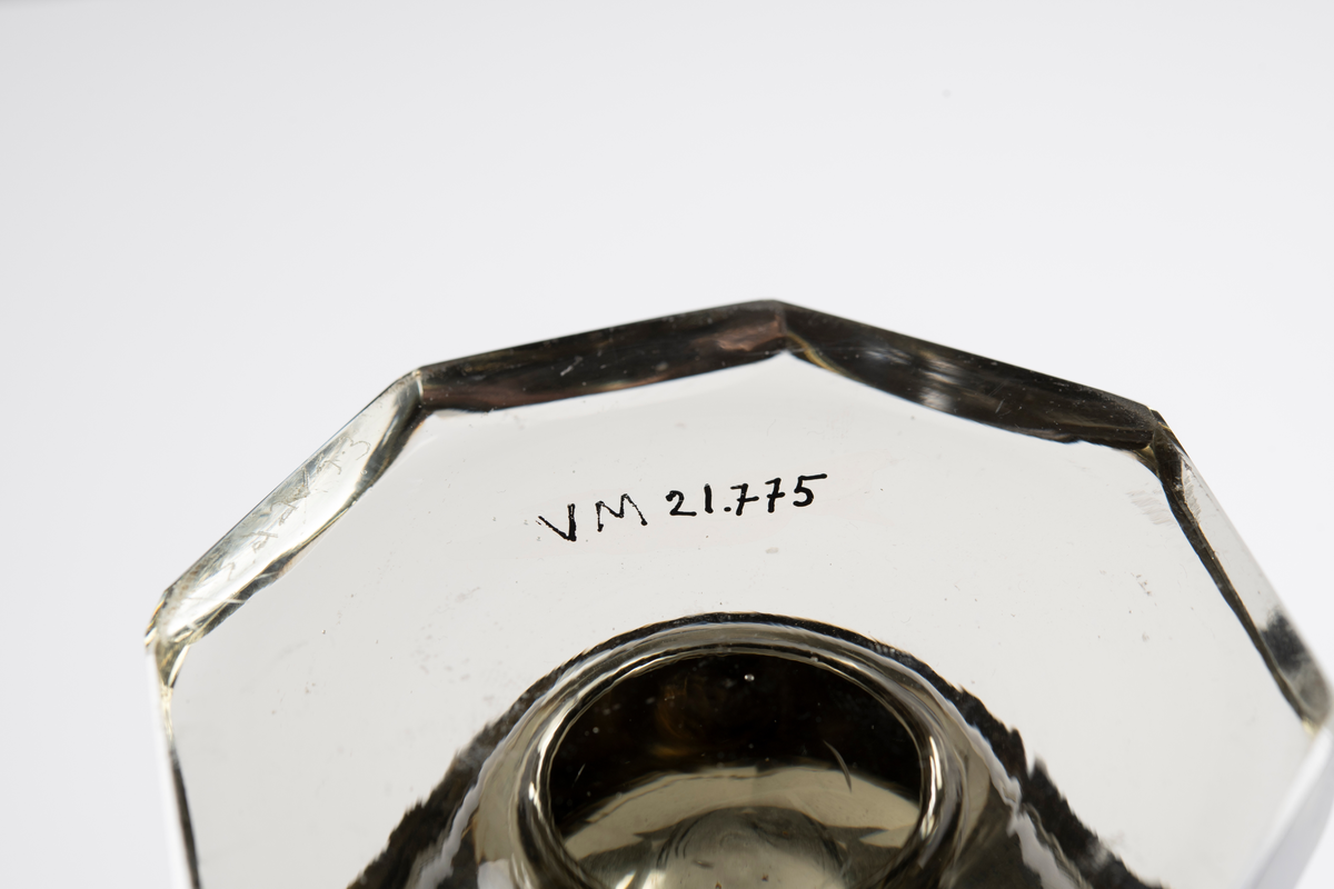 Anmärkning: Vas på fot, rökfärgad glas, åttkantig, indragen upptill samt planslipad mynningskant.
Lagad.