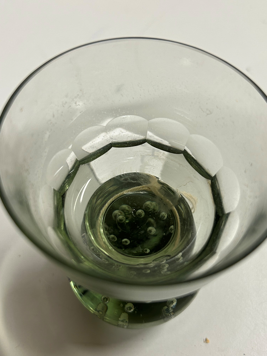 Dricksglas med gröntonat glas. Klotformad fot med luftblåsor. Kupa med olivslipad dekorbård.