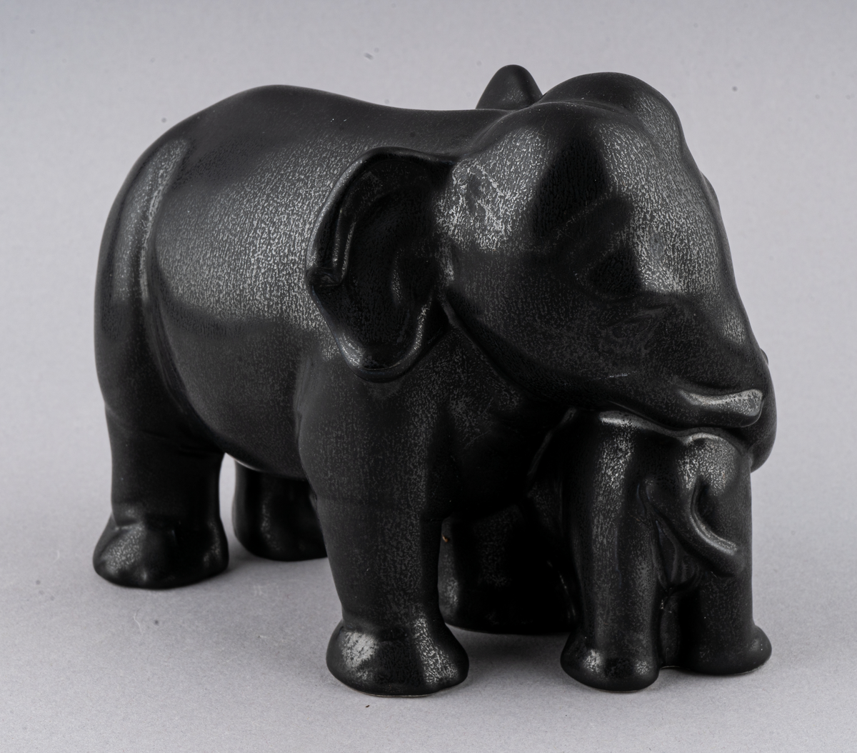 Figurin av flintgods formgiven av Dorothy Clough för Gefle Porslin 1956. Glasyr Mangania. En elefant med sin kalv.