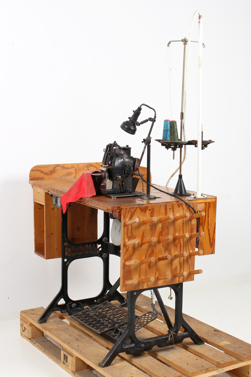 Elektrisk symaskin på tresokkel. tre spoler, spoleverk og lampe.