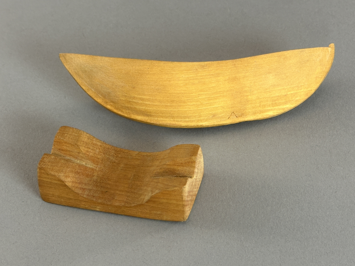 Båtmodell av två olika träslag, skuren i ett stycke med separat ställning.