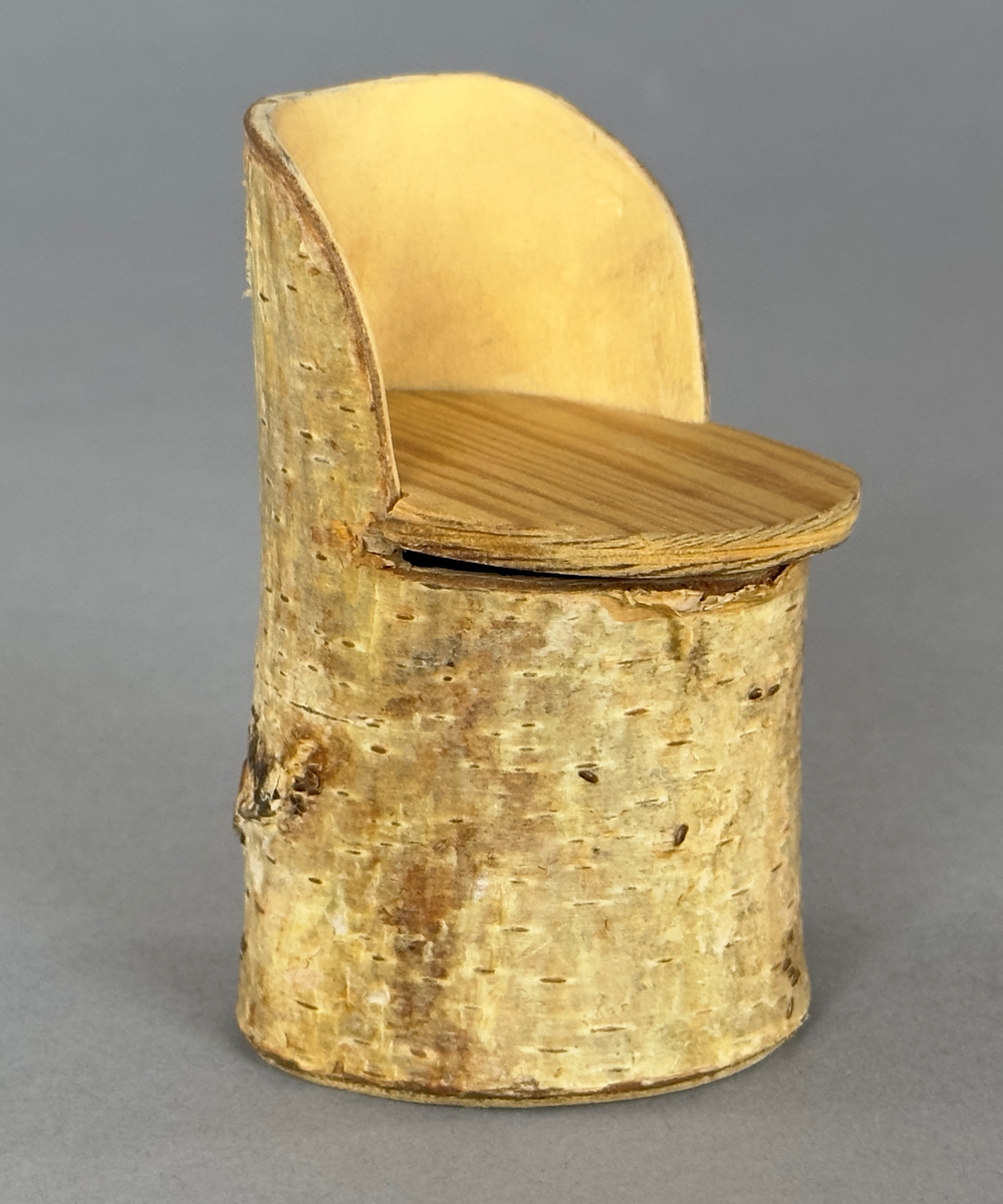 Leksaksstol i trä med löstagbar sits av playwood. Botten/undersida är av kartong.