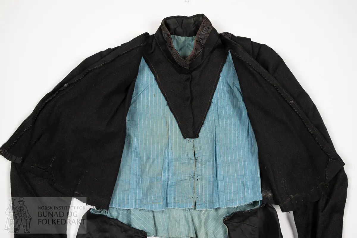 Kjoleliv av svart, kypertvevd ull. 
Kanta med svarte ullbånd med innvevd svart mønster. 
Foret er av bomullslerret med blå bunn, og smale hvite striper.
Midt foran lukkes dette stoffet som en bluse, med hekter. Øverst er det påsydd en skrå kant av det svarte stoffet, dette lukkes med trykknapper.
Livet har høy hals, kanta med bånd, denne lukkes med hekter. Over dette legges nok et lag med det svarte ullstoffet, dette lukkes midt foran med en trykknapp. Og gir en v-ringing som gjør halsen og deler av det svarte stoffet under synlig. 
Livet har et legg på hver skulder, som er med på å gi volum til brystpartiet.
Tosømsermer med litt puff, kanta nederst med bånd.
Nederst er det festa en kappe av svart bomullssateng, denne samler vidden i livet.
Midt bak er det festa tre hekter øverst på denne kappa. 
Kappa er delvis spretta av, den henger ikke lenger på livet foran. 
Nederst på ermene er livet fora med den samme svarte bomullsatengen som kappen er sydd av.
Maskinsydd med noen håndsydde detaljer.