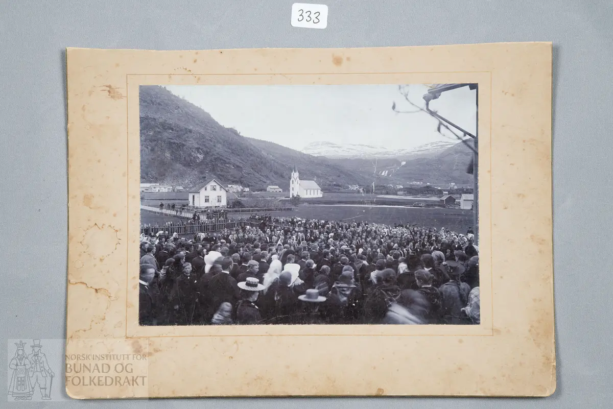 Fotografi. Forsamling, veg, bygninger. Strandebarm kirke i bakgrunnen.
Skrevet bak: 17. mai 1905 eller 1914? Avst. 1905 republikk/konged.?