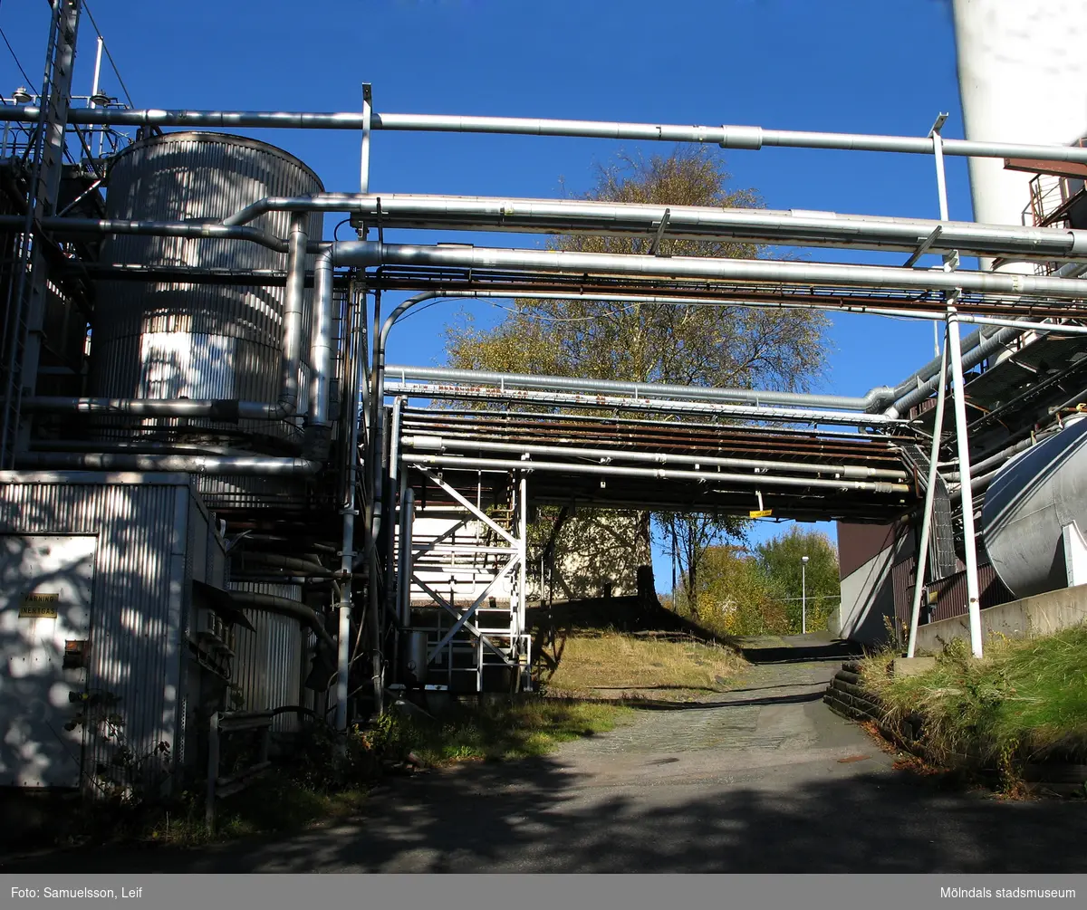 Äldre stenbelagd väg intill byggnader vid Soabs industrianläggning i Mölndals Kvarnby, år 2007. Över vägen löper en mängd rörledningar. Anläggningen användes vid fototillfället av Hexion Speciality Chemicals Sweden AB.
