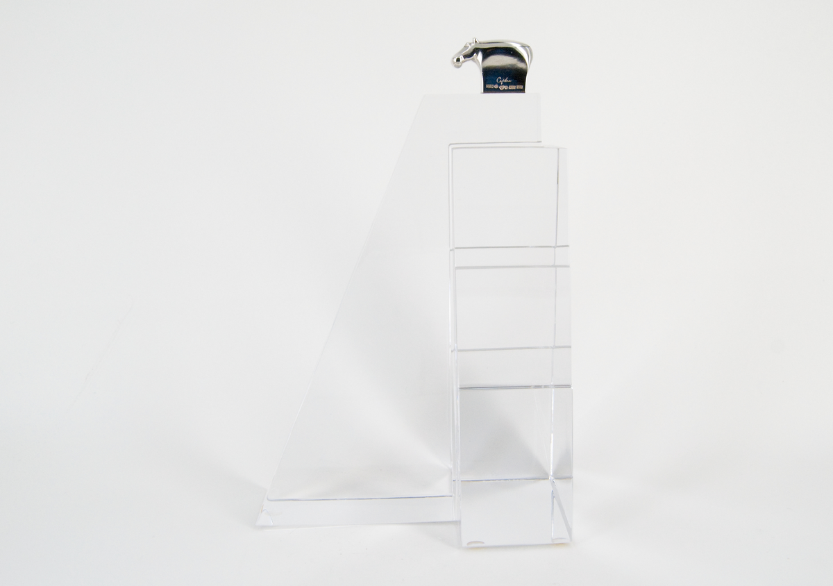 Skulptur, "Litet tempel", i silver och glas, av Gunnar Cyrén, 1989. Högt glasfundament med T-formad bas. Avsmalnande, delvis trappstegsformad, uppåt. Krönt av liten flodhäst i silver.