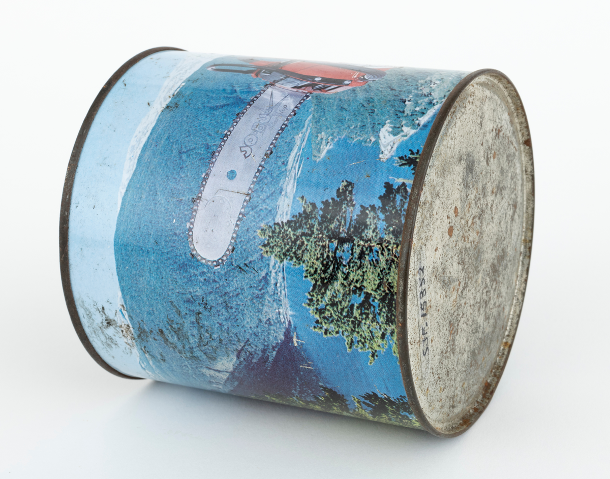 En sylindrisk boks, blikkboks, reklamemateriell, fra motorsagprodusenten / salgsbedriften Jo-Bu i Drøbak. Boksen har påtrykt firmaets logo og et bilde av motorsaga Jo-Bu (JOBU) L7. Saga svever over et norsk fjordlandskap med skogkledte fjellsider i forgrunnen og snødekte fjelltopper i bakgrunnen. Logoen som er påtrykt blikkboksen består av navnet JO BU med et grantre mellom JO og BU. Navnet omkranses av et sagkjede. Under "sagkjedet" står teksten: "OSLO-Norway".

Boksen har ukjent innhold, men en hører en raslelyd når den ristes.