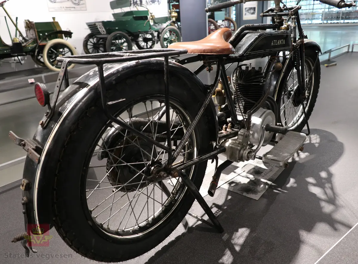 Atlanta. Motorsykkel, svart med hvit staffering. Motoren er en ensylindret bensindrevet forbrenningsmotor fra Villiers med et sylindervolum på 342 ccm (350) og en effekt på 8-12 hk. Albion 3-gir med clutch og kick starter. Sykkelen mangler noen deler. Atlanta med Villiers motor benevnes gjerne som Atlanta-Villiers. Merkingen CZ på veivhuset og Mark IXB på sylinder beviser at dette er en Villiers på 342 ccm fra perioden 1926-1929 (trolig org. motoren).