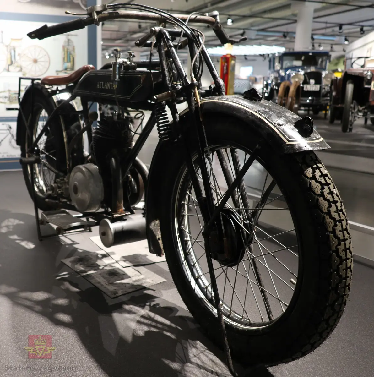 Atlanta. Motorsykkel, svart med hvit staffering. Motoren er en ensylindret bensindrevet forbrenningsmotor fra Villiers med et sylindervolum på 342 ccm (350) og en effekt på 8-12 hk. Albion 3-gir med clutch og kick starter. Sykkelen mangler noen deler. Atlanta med Villiers motor benevnes gjerne som Atlanta-Villiers. Merkingen CZ på veivhuset og Mark IXB på sylinder beviser at dette er en Villiers på 342 ccm fra perioden 1926-1929 (trolig org. motoren).