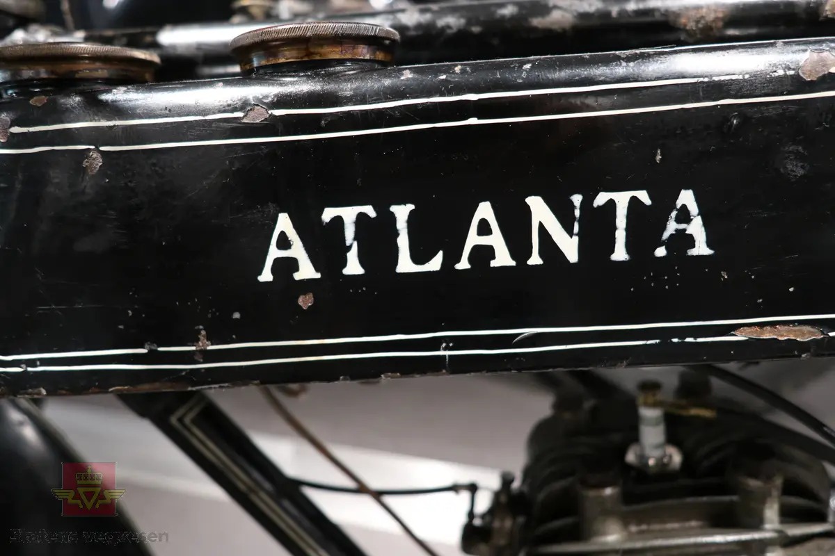 Atlanta. Motorsykkel, svart med hvit staffering. Motoren er en ensylindret bensindrevet forbrenningsmotor fra Villiers med et sylindervolum på 342 ccm (350) og en effekt på 8-12 hk. Albion 3-gir med clutch og kick starter. Sykkelen mangler noen deler. Atlanta med Villiers motor benevnes gjerne som Atlanta-Villiers. Merkingen CZ på veivhuset og Mark IXB på sylinder beviser at dette er en Villiers på 342 ccm fra perioden 1926-1929 (trolig org. motoren).
