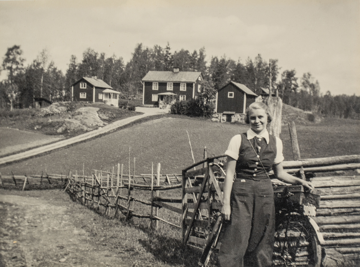 Svartvitt fotografi i ram.

Fotografi av en kvinna som står lätt lutad mot en cykel i en lantlig miljö. I bakgrunden finns en gärdesgård, väg och tre byggnader. 
Kvinnan är klädd i vida byxor, knäppt väst och kortärmad blus med krage. Kvinnan heter Ulla Zander och det är gården Holmbo i Hannäs i bakgrunden.

Fotografiet sitter i en brun- och guldfärgad ram, tillvekad av trä och ornerad med gips. Ramen har ett bakstycke av brunmarmorerad papp med ett ståstöd. Framför fotografiet sitter ett glas. Fotografiet, glaset och bakstycket skjuts in i ramens ena kortsida. Ramen är ihopspikad med nubb i hörnen.

Fotografiet finns i arbetarhemmet Solliden, som flyttades till Gamla Linköping 1987. I Solliden bodde Nils Andersson med sina föräldrar, Albin, som var diversearbetare, och Elisabeth, som var hemsömmerska. Hemmet har bevarats nästan helt orört sedan andra hälften av 1920-talet, då familjen Andersson flyttade in i  det nybyggda huset, som tidigare låg på Sandtorpsgatan i Linköping.

Ulla, på fotografiet, var kusin till Nils och hon bodde under perioder i barndomen i Solliden. Gården Holmbo var Elisabeths och Ullas pappa Enochs föräldrahem.