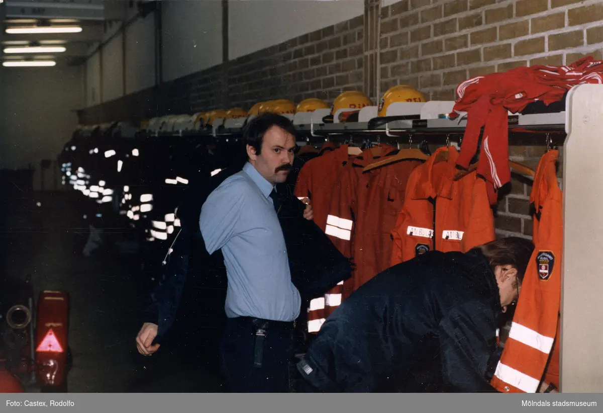 Mölndals brandstation i Trädgården, Mölndal, på 1980-talet. Två brandmän tar på sig kläder.