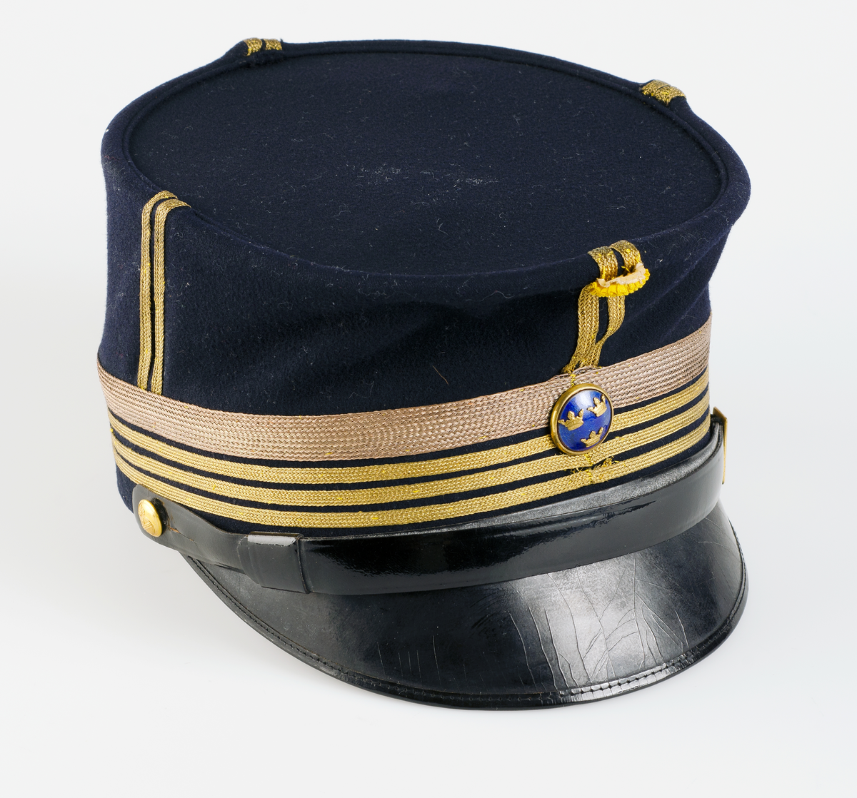 Mössa med skärm som tillhör översteuniform, M/ä för Upplands Regemente, I 8 i Uppsala, mörkblå med guldgaloner och guldknappar med riksäpplet.