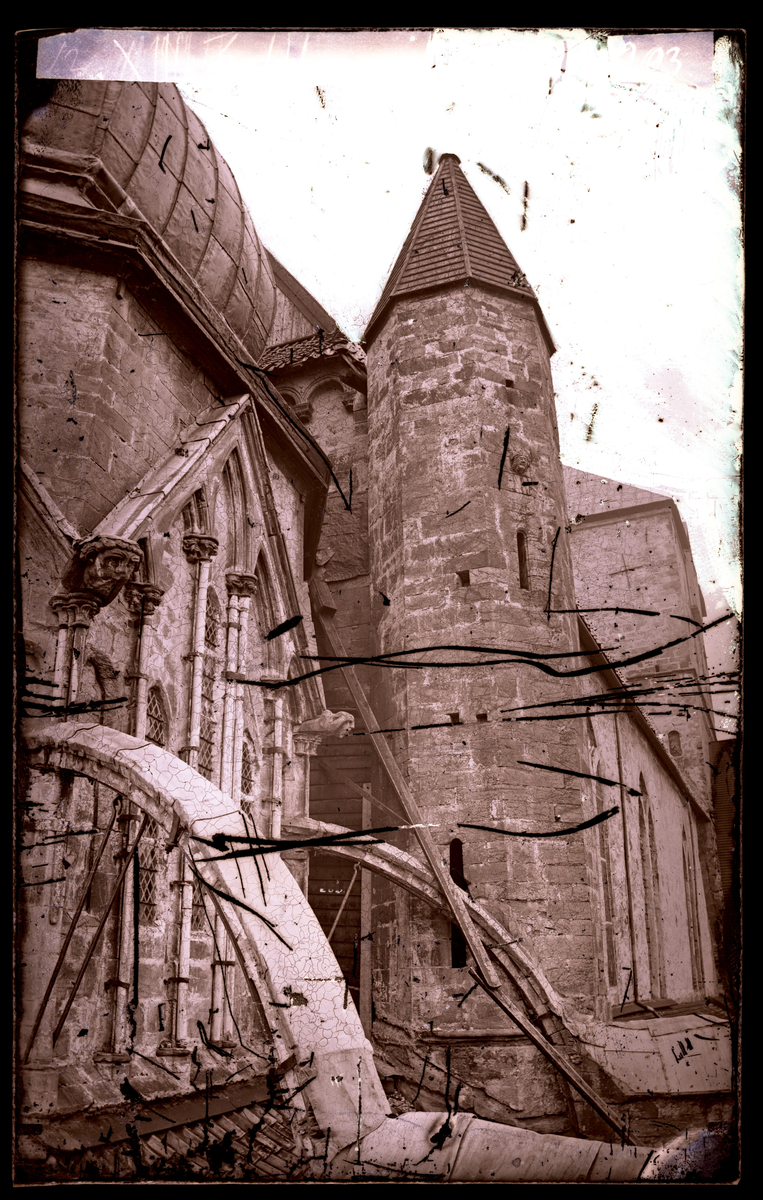Oktogonen i Nidarosdomen. Veggparti mot nord i klerestoriehøyde, med nordre kortårn. Strebebuer og gotisk skulptur. Deler av stillas ca. midt i bildet. Bildet er tatt før restaurering. Oktogonen ble restaurert i perioden 1872-1877. Øverst til venstre skimtes den gamle barokke takkuppelen som ble fjernet i 1876.