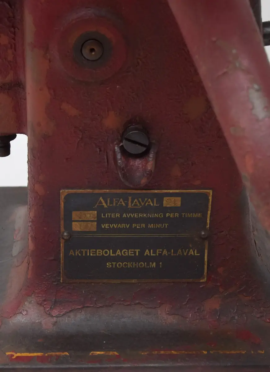 Separator Alfa-Laval 21 bestående av a) växelhus med vev och stativ b) mjölkbehållare, c-d) urtappningsanordning för mjölk och smörfett. 

a) växelhuset står på en rektangulär platta med hål för fyra fästeskruvar. Plattan övergår i en sockel med ovalt tvärsnitt i vars överdel infattats växelhus med kantkuggat hjul drivet av en handvev på motsatta sidan. Sockeln avslutats upptill i ett trearmat stativ. Samtliga delar av gjutjärn, rödlackerade. Tillverkarskylten av svart lackerad mässing placerad på sockelns nedre del under vevfästet. 

b) mjölkbehållaren 35 cm i diameter, höjd 18,9 cm. Den övre kanten något inåtböjd. Firmanamnet Alfa-Laval 21 i relief med 2 cm höga bokstäver. Under texten en avtappningskran med utsläppet i behållarens botten, placerat något på ena sidan. 

c) urtappningsanordning för mjölk består av en cylindrisk behållare 13,5 cm i diameter med spillrör 16,7 cm långt samt en flottör inne i cylidnern. 

d) urtappniningsanordning för grädde (mjölkfett) försedd med spillrör såsom föregående. En rund samlare med en tratt i mitten. Tratthållet 4,5 cm i diameter. 