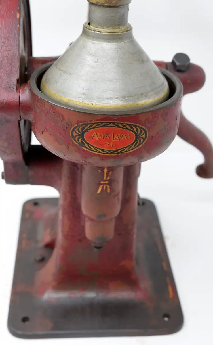 Separator Alfa-Laval 21 bestående av a) växelhus med vev och stativ b) mjölkbehållare, c-d) urtappningsanordning för mjölk och smörfett. 

a) växelhuset står på en rektangulär platta med hål för fyra fästeskruvar. Plattan övergår i en sockel med ovalt tvärsnitt i vars överdel infattats växelhus med kantkuggat hjul drivet av en handvev på motsatta sidan. Sockeln avslutats upptill i ett trearmat stativ. Samtliga delar av gjutjärn, rödlackerade. Tillverkarskylten av svart lackerad mässing placerad på sockelns nedre del under vevfästet. 

b) mjölkbehållaren 35 cm i diameter, höjd 18,9 cm. Den övre kanten något inåtböjd. Firmanamnet Alfa-Laval 21 i relief med 2 cm höga bokstäver. Under texten en avtappningskran med utsläppet i behållarens botten, placerat något på ena sidan. 

c) urtappningsanordning för mjölk består av en cylindrisk behållare 13,5 cm i diameter med spillrör 16,7 cm långt samt en flottör inne i cylidnern. 

d) urtappniningsanordning för grädde (mjölkfett) försedd med spillrör såsom föregående. En rund samlare med en tratt i mitten. Tratthållet 4,5 cm i diameter. 