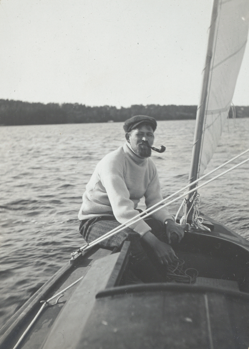 Kanotseglare, ev. Erik "Boa" Boström, rökandes pipa i sittbrunnen på segelkanot.