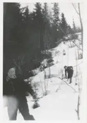To kvinner går gjennom snøen ned en bakke, de smiler og ler.