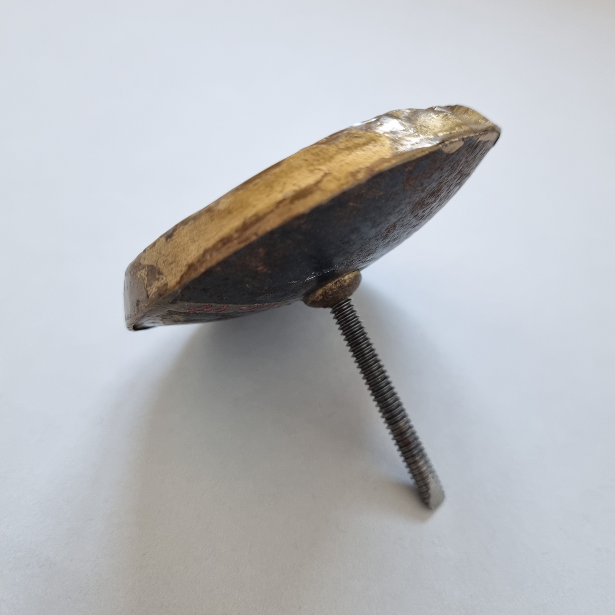 Gardinstångsknopp i guldfärgad metall.