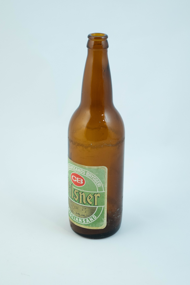 Brune glassflaskre med grønn papiretikett med hvit og lysebrun skrift. På den ene flasken er etiketten falmet hvit.